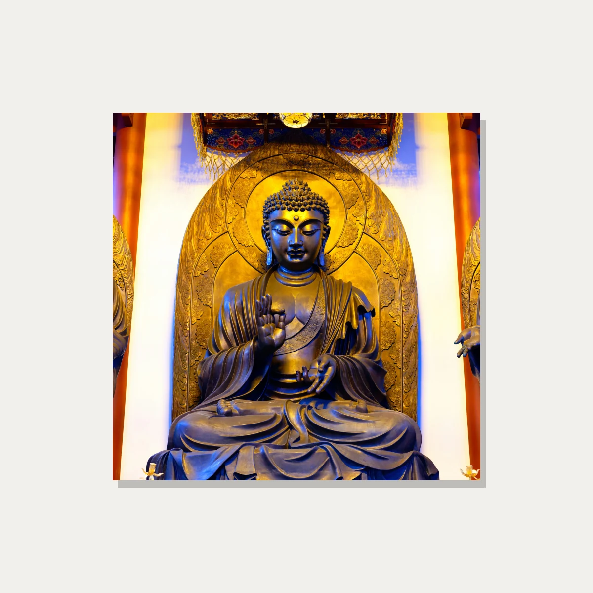A majestic golden bronze statue of Gautama Buddha seated in meditation inside a temple shrine with warm overhead lighting. | PrintPosters.in
