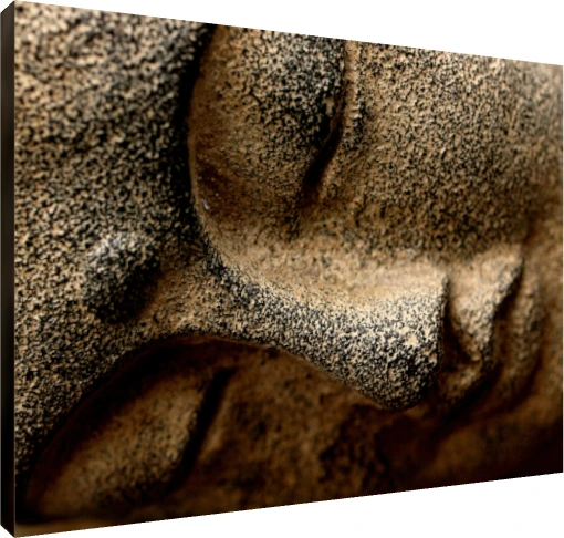Extreme close-up of a textured stone sculpture of Lord Buddha's serene face, showing his closed eye and nose. | PrintPosters.in